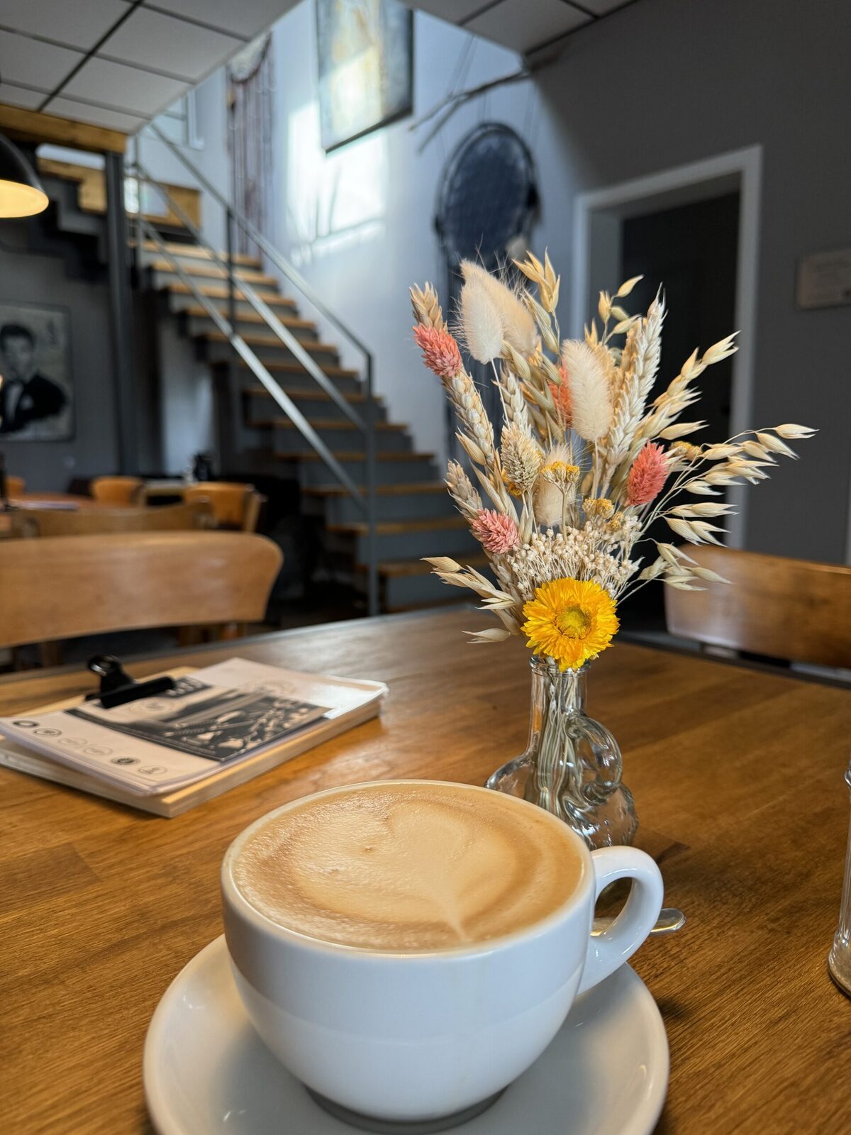 Cappuccino auf Holztisch mit Trockenblumen